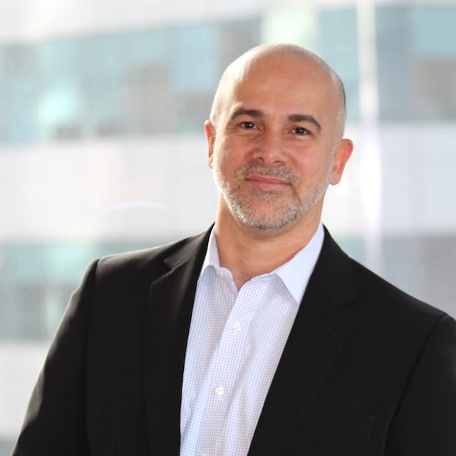 marcelo_paiva Man wearing a black suit and white shirt in front of a building.